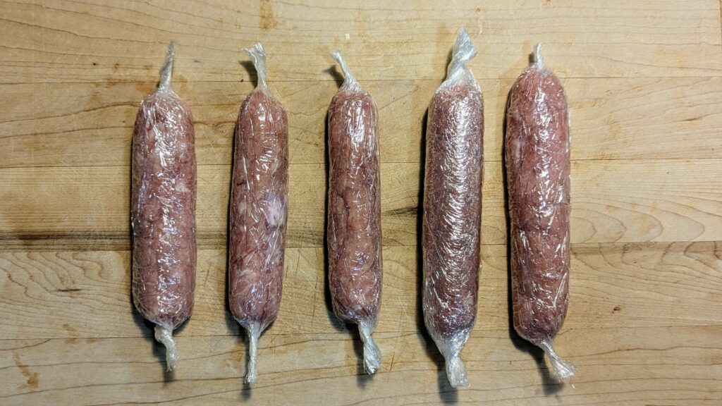 cinque-wurstel-fatti-in-casa-arrotolati-nella-pellicola-per-microonde-pre-cottura